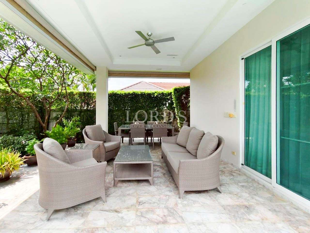 Covered villa patio with wicker sofa set, coffee table, and outdoor dining area.