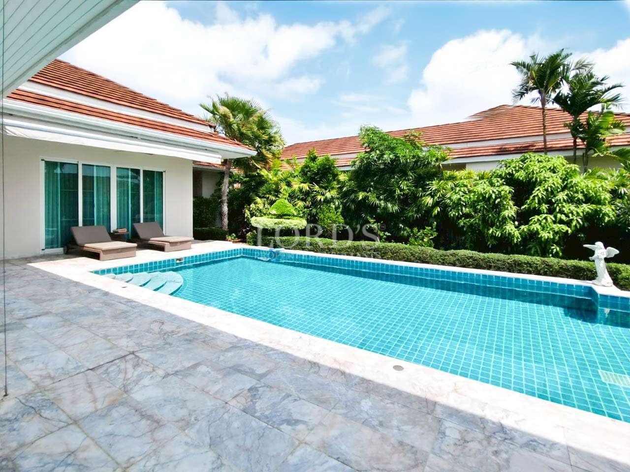 Luxury poolside with lush greenery.