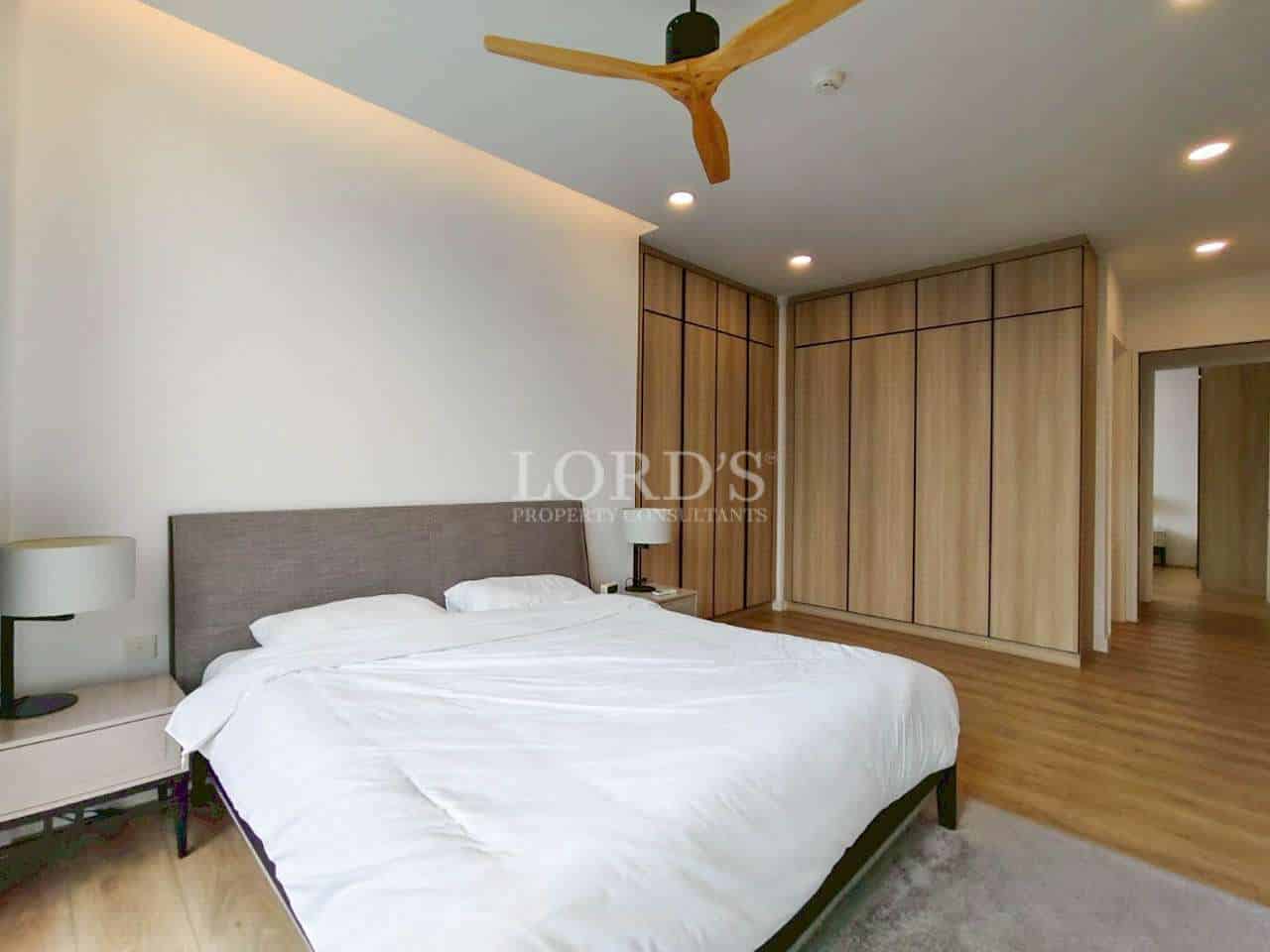 Modern bedroom with double bed, wooden wardrobes, and ceiling fan.