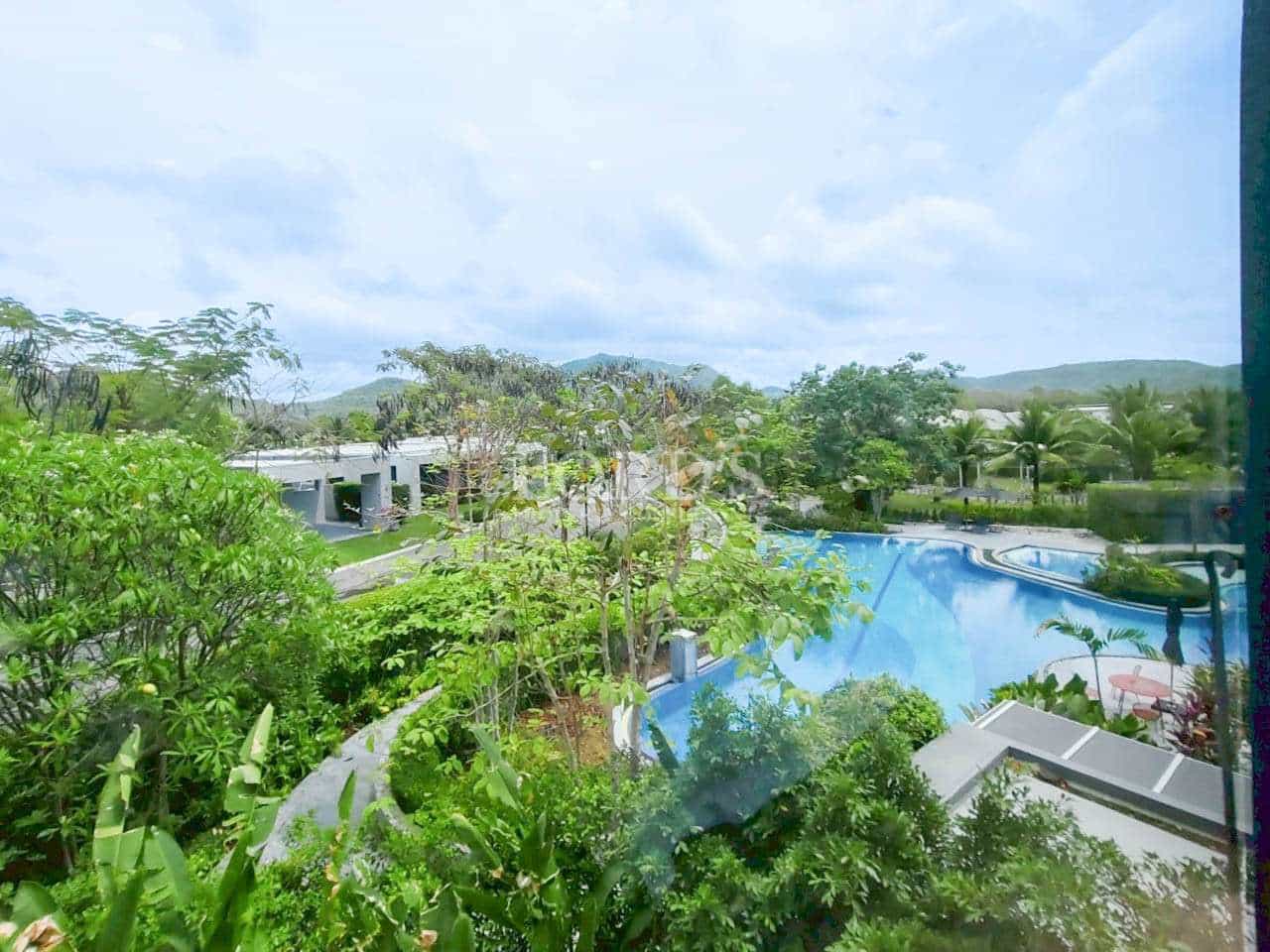 Resort-style swimming pool surrounded by lush greenery and scenic landscape.