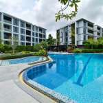 Modern condominium buildings with a resort-style swimming pool and landscaped surroundings.