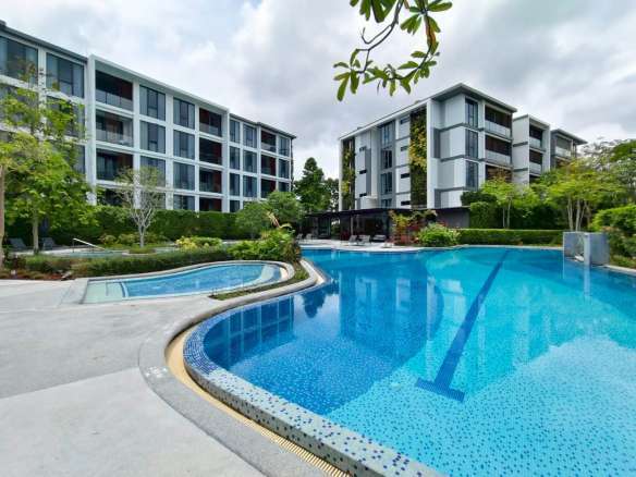Modern condominium buildings with a resort-style swimming pool and landscaped surroundings.