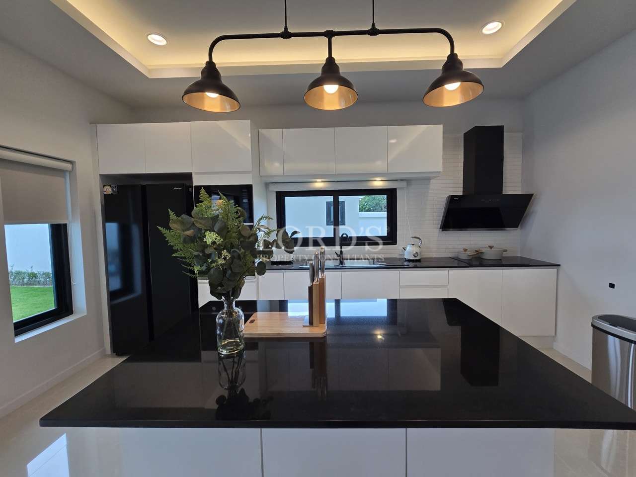 Modern kitchen with black island countertop, pendant lights, white cabinets, and built-in appliances.
