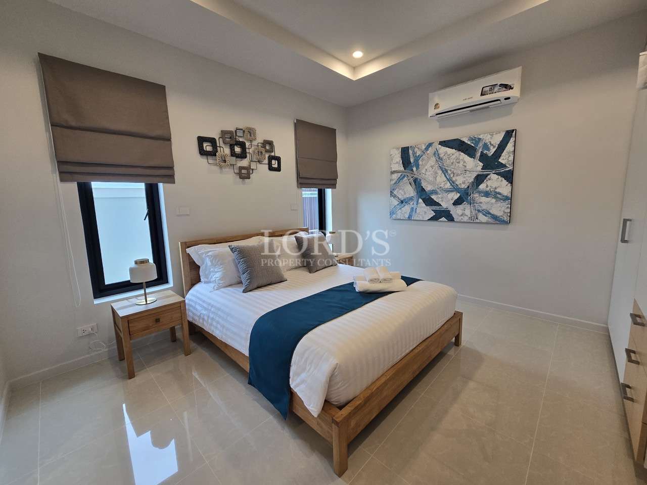 Modern bedroom with wooden bed, air conditioner, bedside table, and abstract wall art.