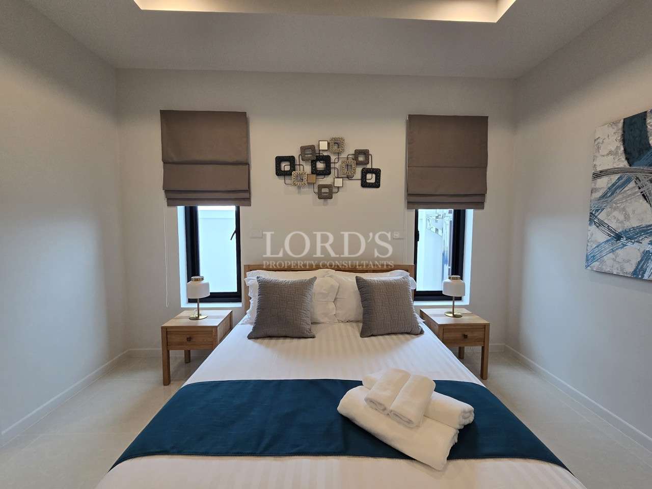 Modern bedroom with double bed, bedside tables, decorative wall art, and soft lighting.