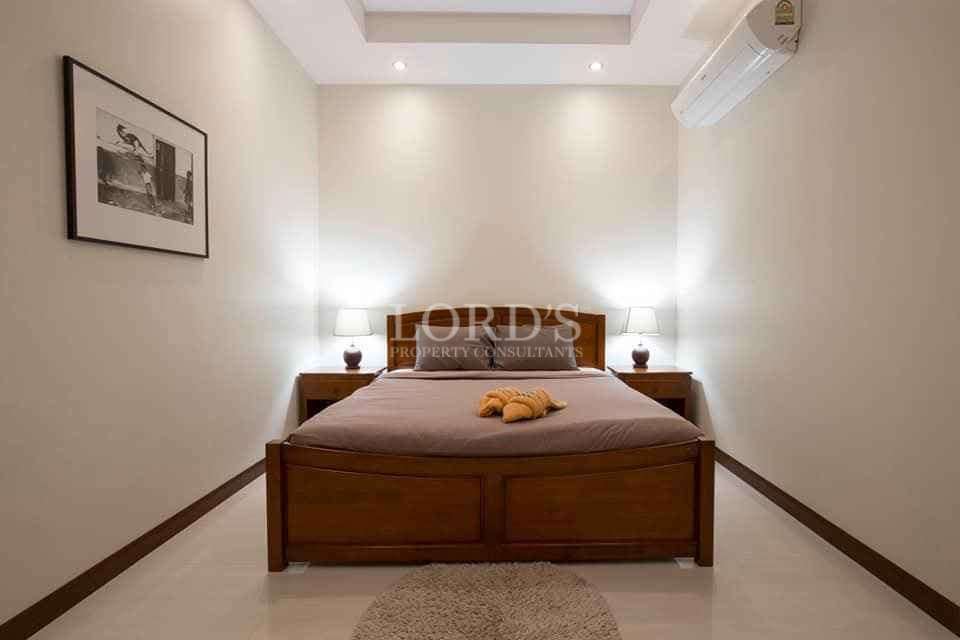 Minimalist bedroom with wooden bed, bedside lamps, and air conditioner.