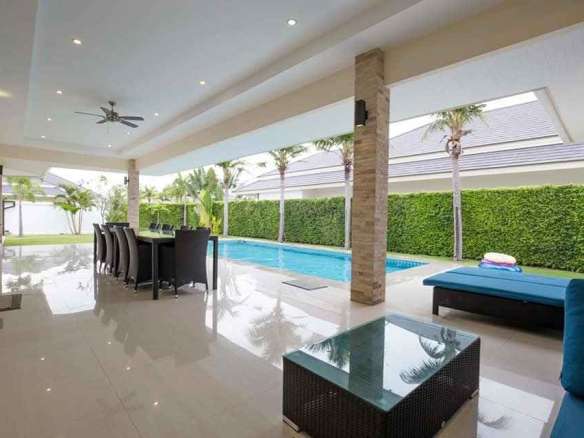 Covered outdoor living area with dining table, sun loungers, and private swimming pool.