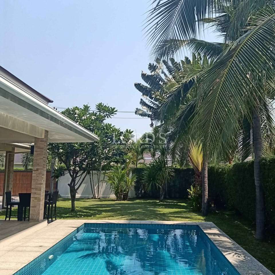 Private swimming pool surrounded by palm trees and tropical garden at a modern villa.
