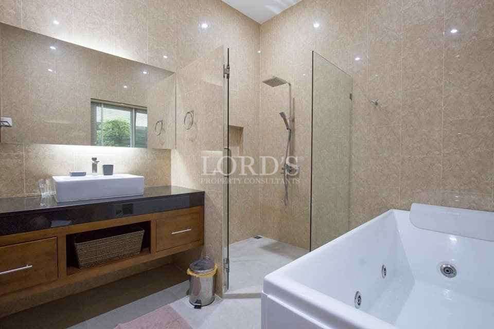 Luxury bathroom with glass shower, bathtub, and wooden vanity.