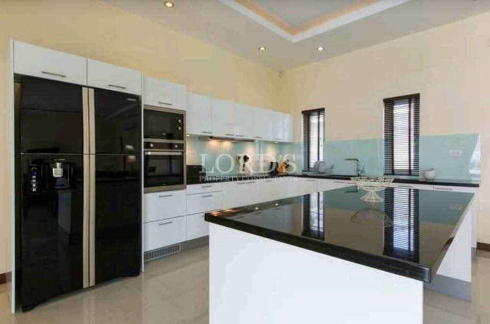 Modern kitchen with island, black countertops, built-in appliances, and white cabinets.