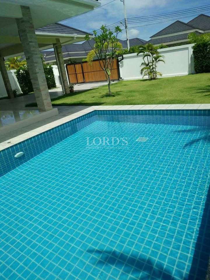 Private swimming pool with blue tiled finish and garden view in a modern villa.