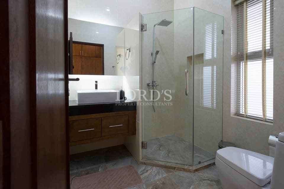 Modern bathroom with glass shower enclosure, wooden vanity, and large window.