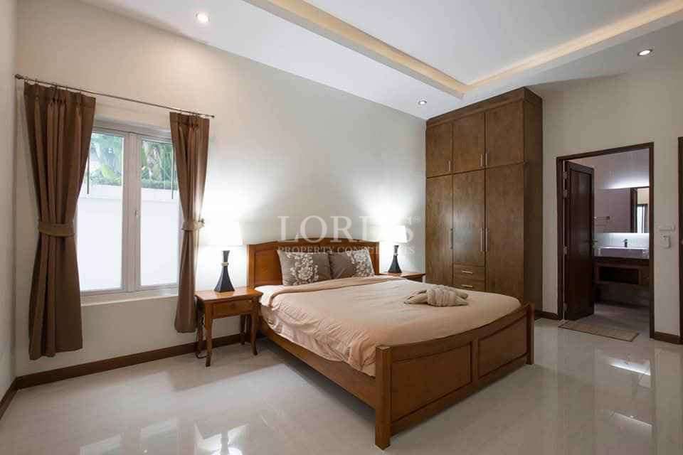 Modern bedroom with wooden bed, bedside tables, wardrobe, and ensuite bathroom.