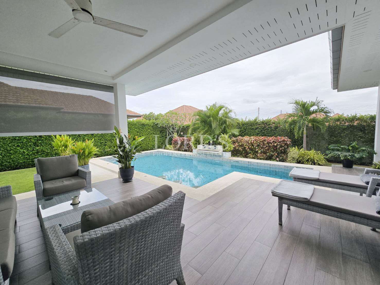 Covered poolside terrace with outdoor seating and private swimming pool in a modern villa.