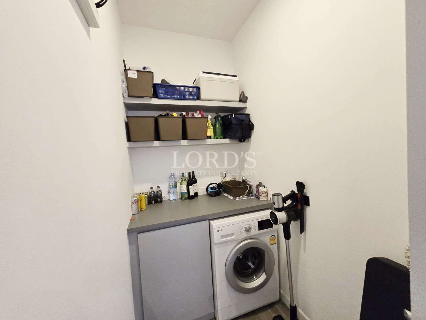 Compact laundry room with washing machine, storage shelves, and countertop