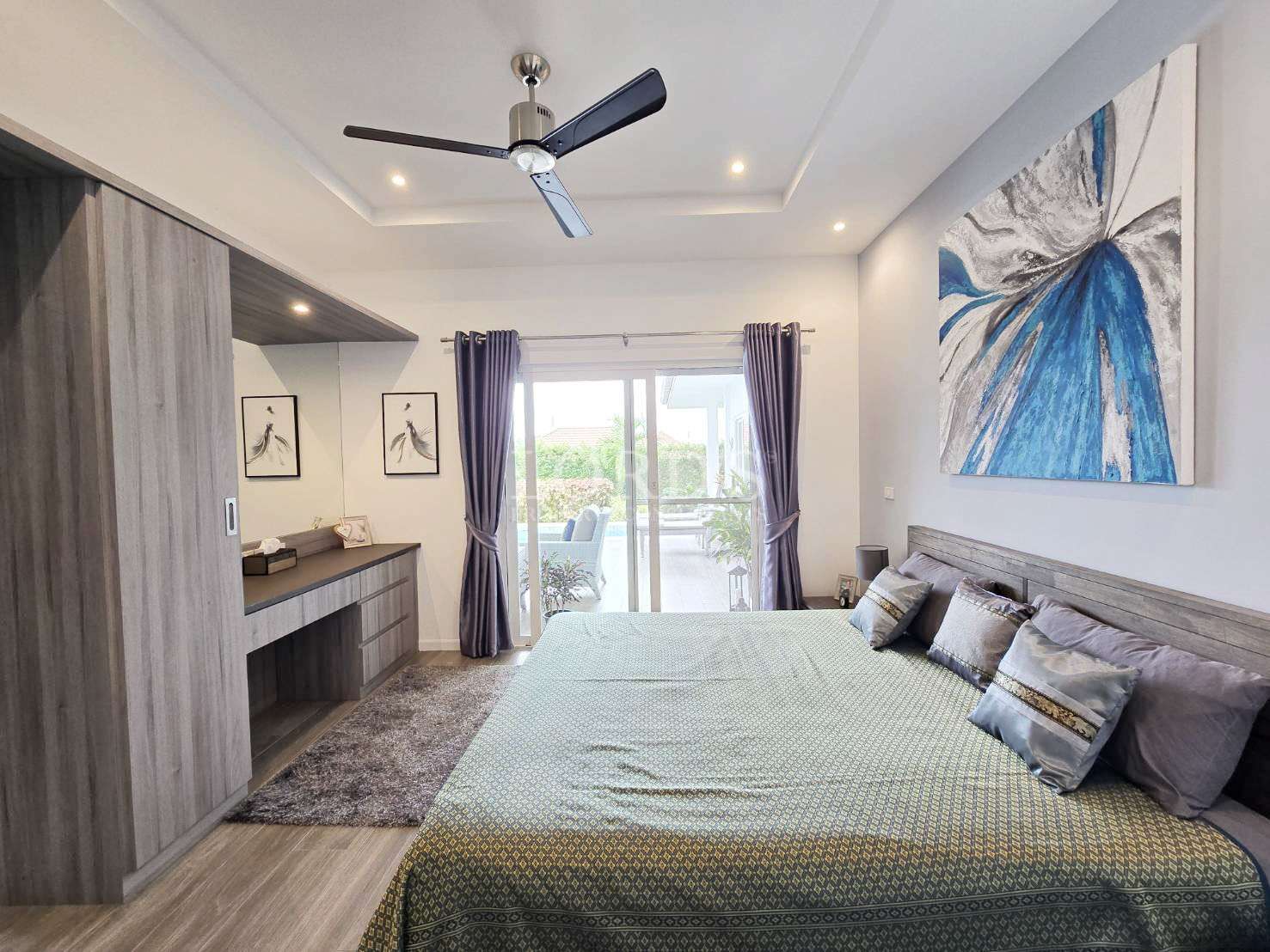 Modern bedroom with double bed, wooden wardrobe, ceiling fan, and sliding glass door opening to a patio