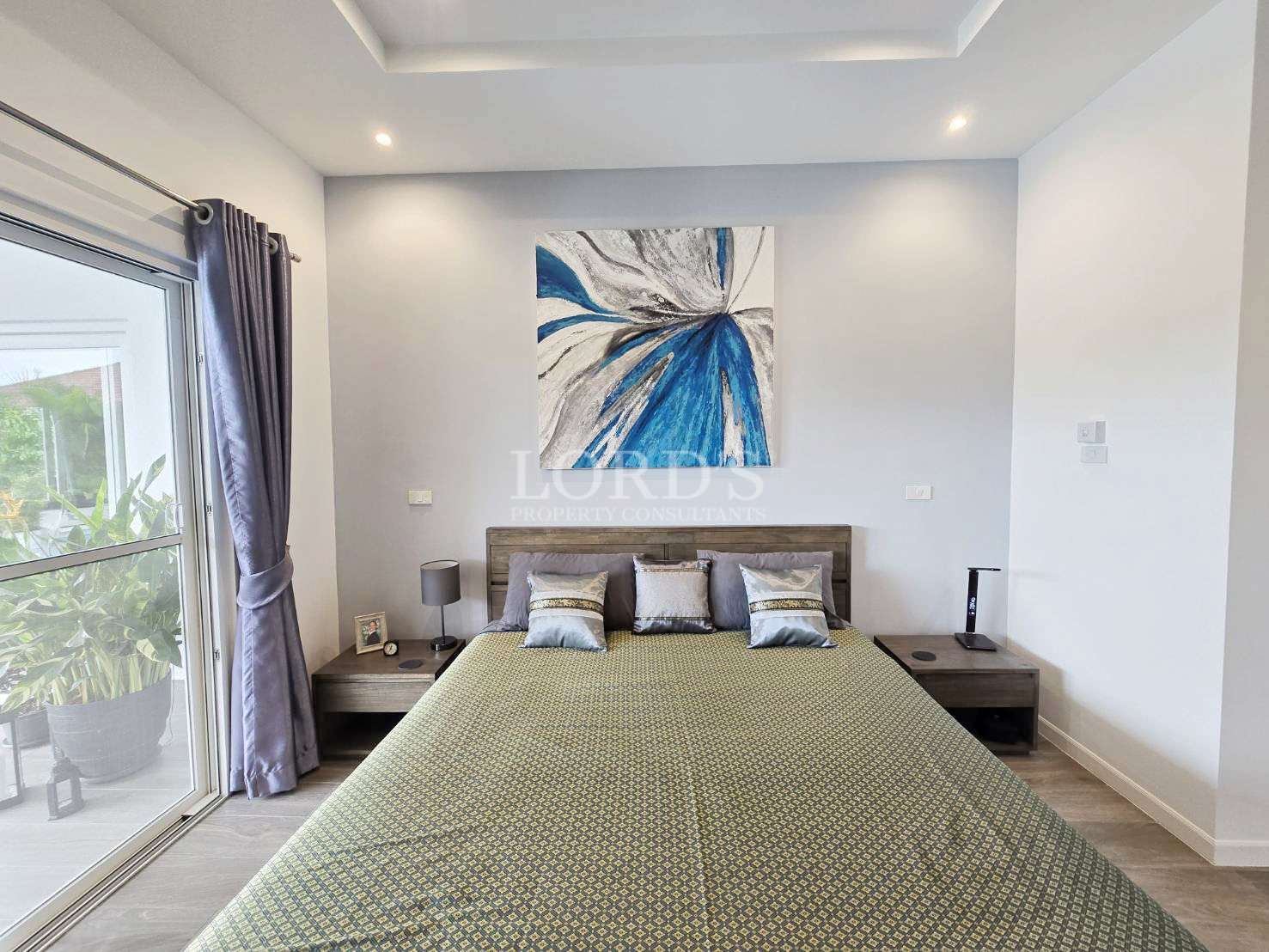 Modern bedroom with double bed, abstract wall art, bedside tables, and natural light.