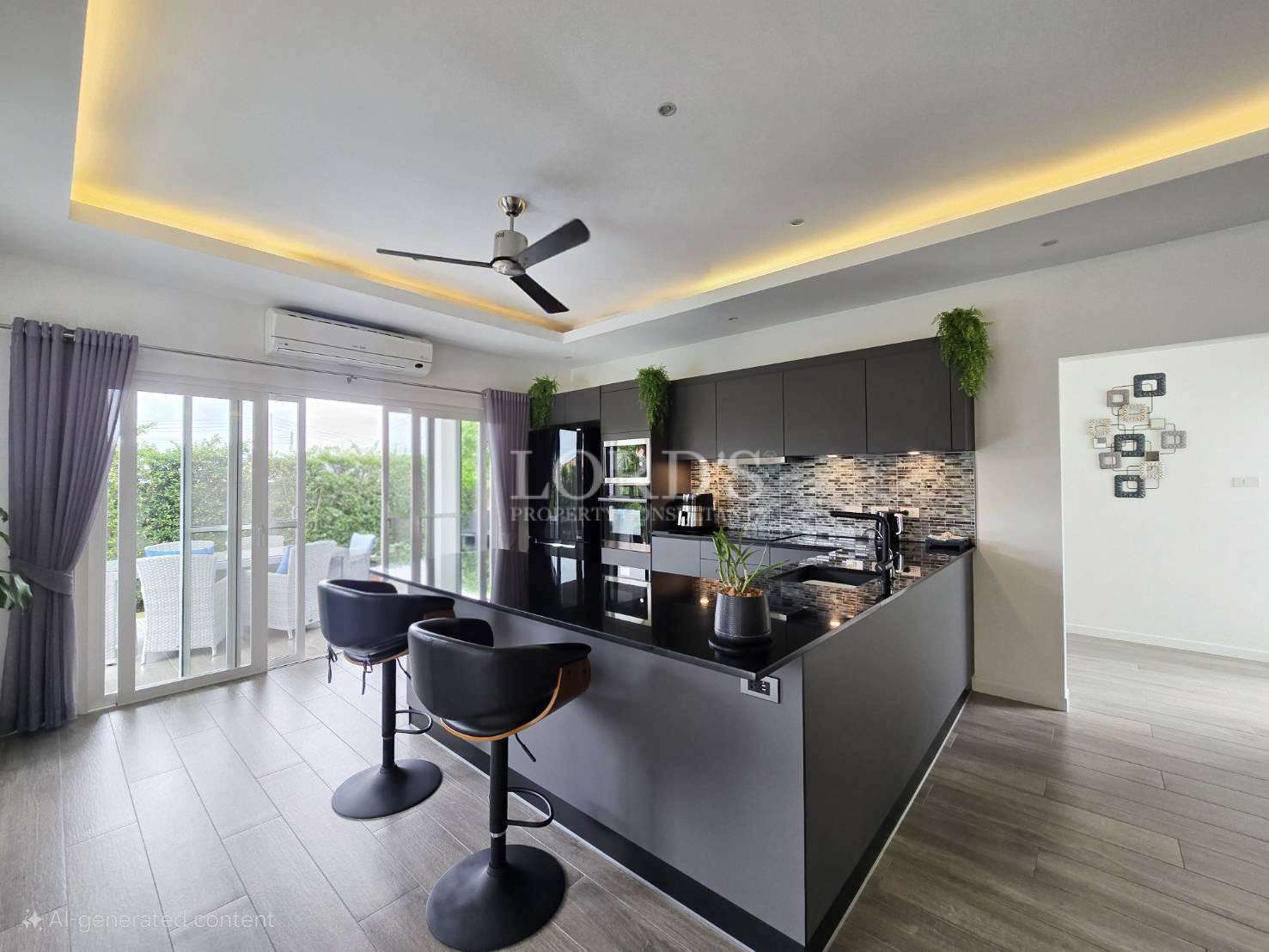 Modern open-plan kitchen with black island, bar stools, and large glass doors opening to the garden.