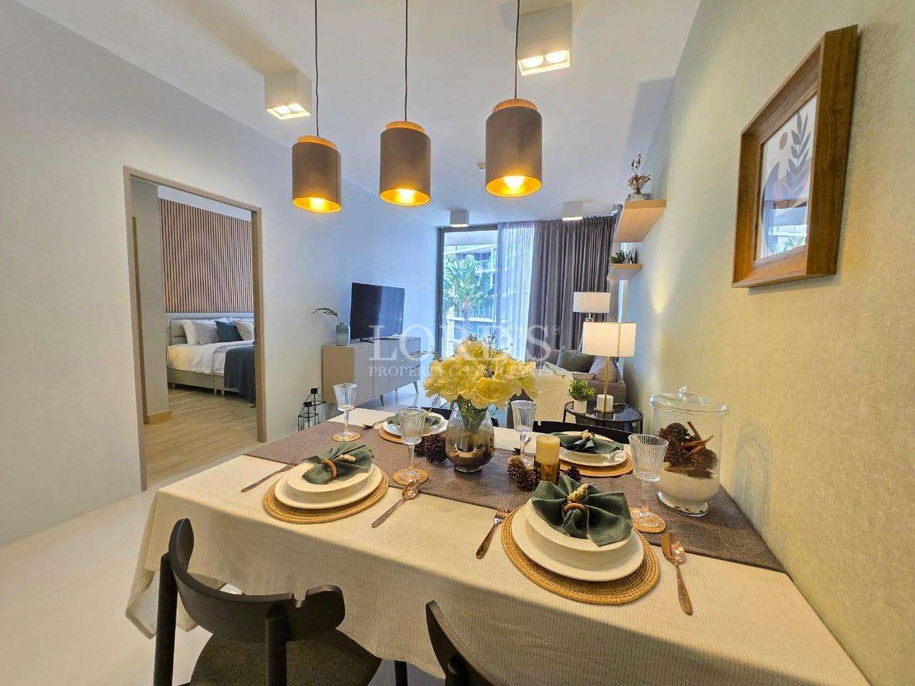 Modern dining area with styled table setting, warm pendant lights, and open-plan living room in a contemporary apartment.