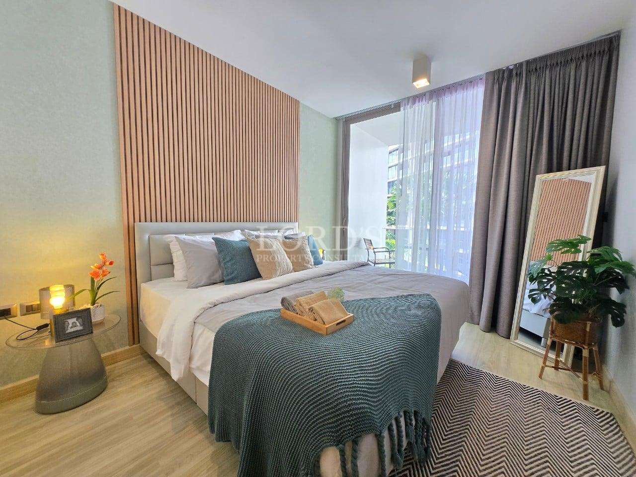 Modern bedroom with wooden slat accent wall, double bed, balcony access, and soft natural lighting.