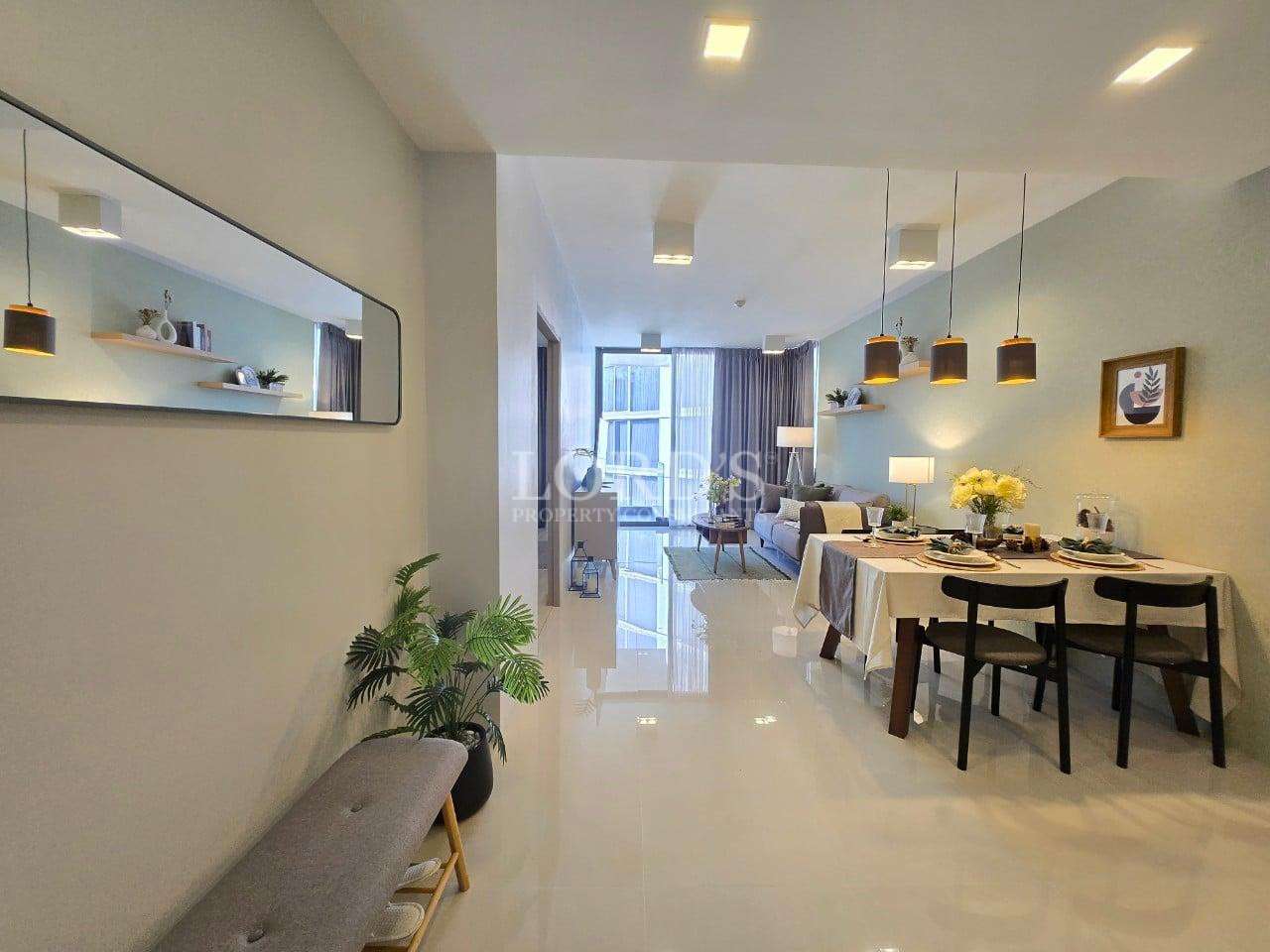 Open-plan dining and living area with modern lighting, dining table, sofa, and balcony view.