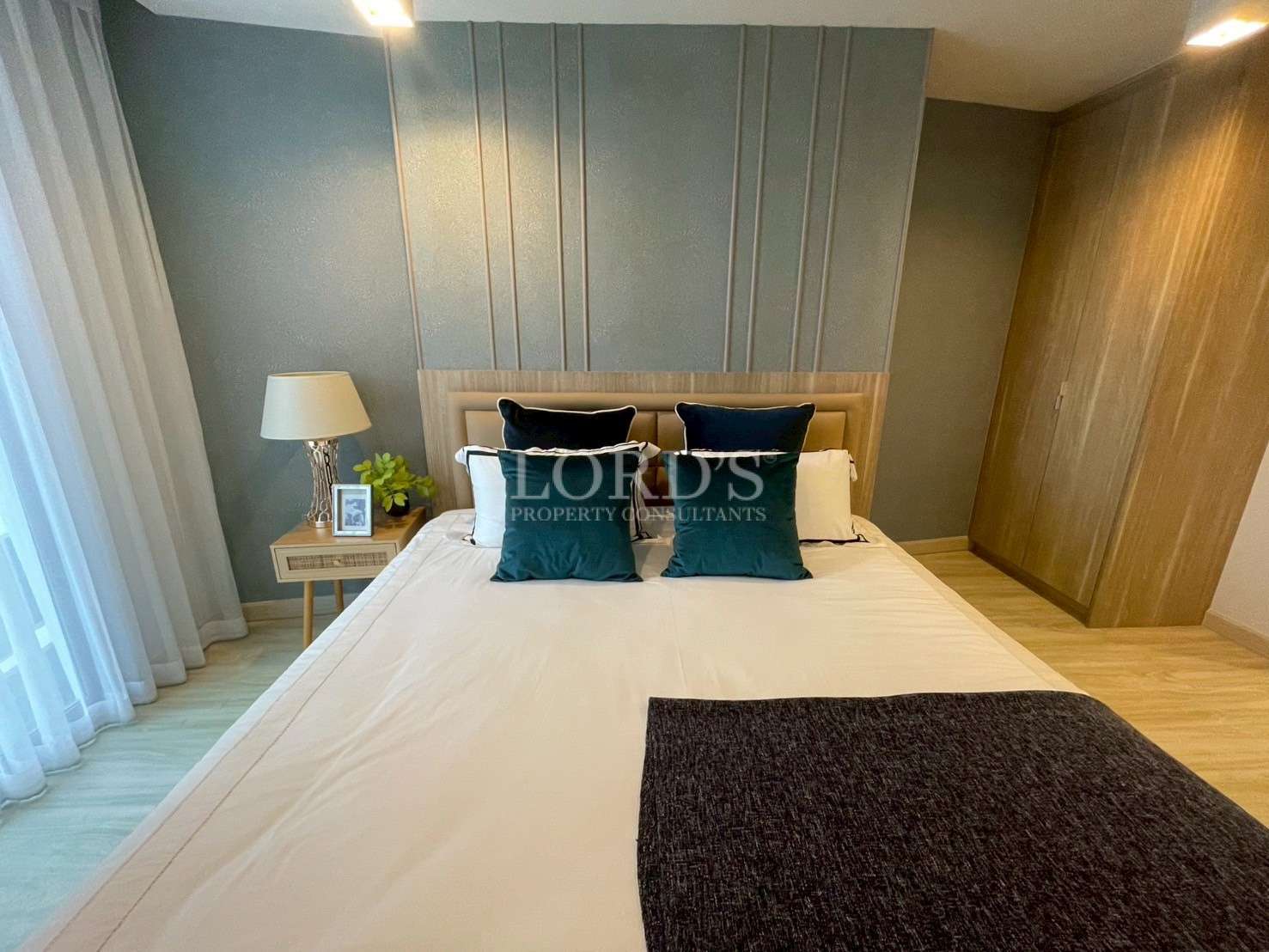 Modern bedroom with double bed, padded headboard, bedside table, and soft ambient lighting.