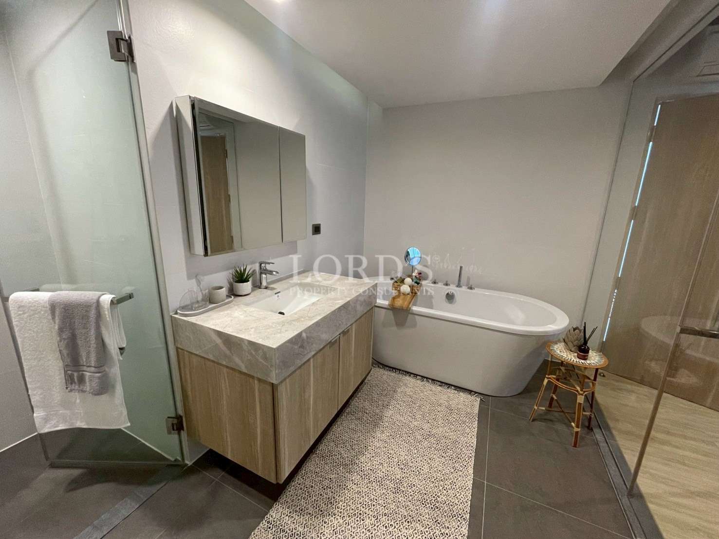 Modern bathroom with vanity sink, freestanding bathtub, glass shower, and wooden cabinetry.