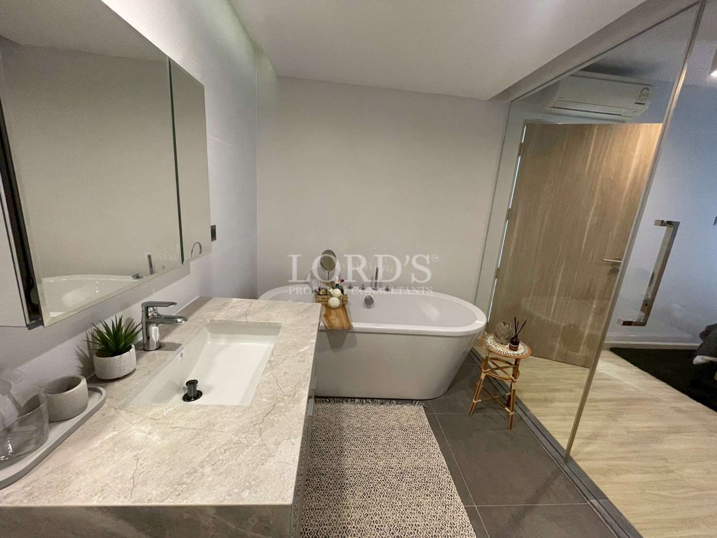 Modern bathroom with freestanding bathtub, vanity sink, large mirror, and glass shower partition.