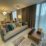 Modern living room with gray sofa, coffee table, patterned rug, and large window curtains.