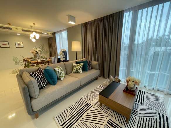 Modern living room with gray sofa, coffee table, patterned rug, and large window curtains.
