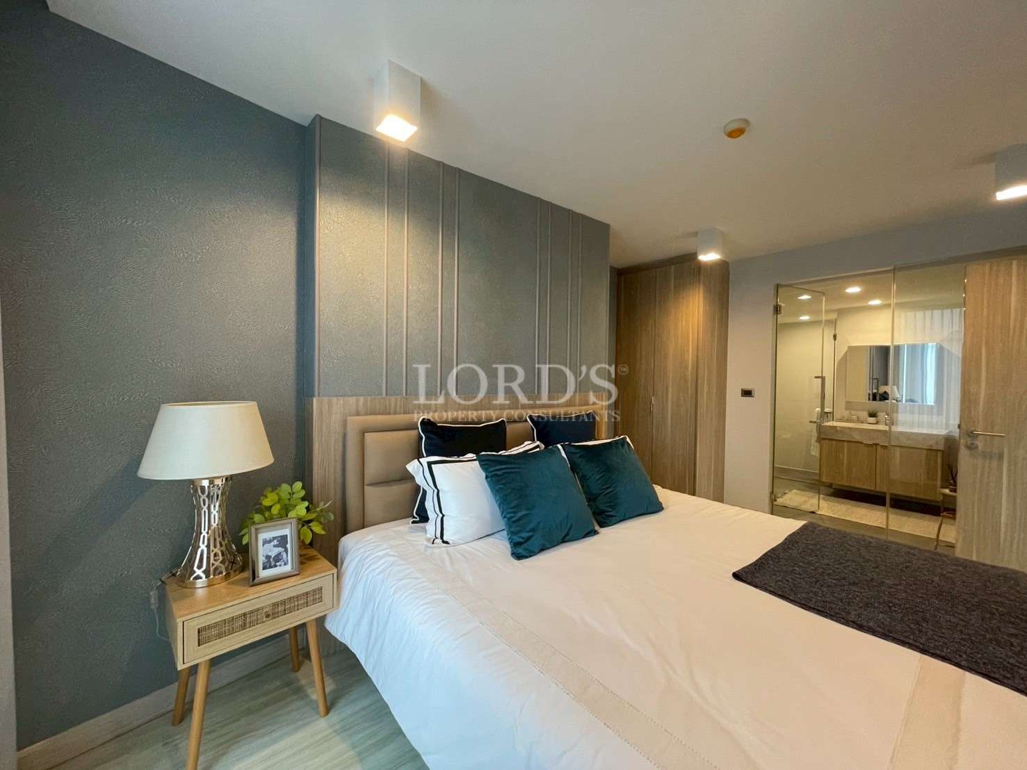 Modern bedroom with double bed, bedside table, soft lighting, and en-suite bathroom.