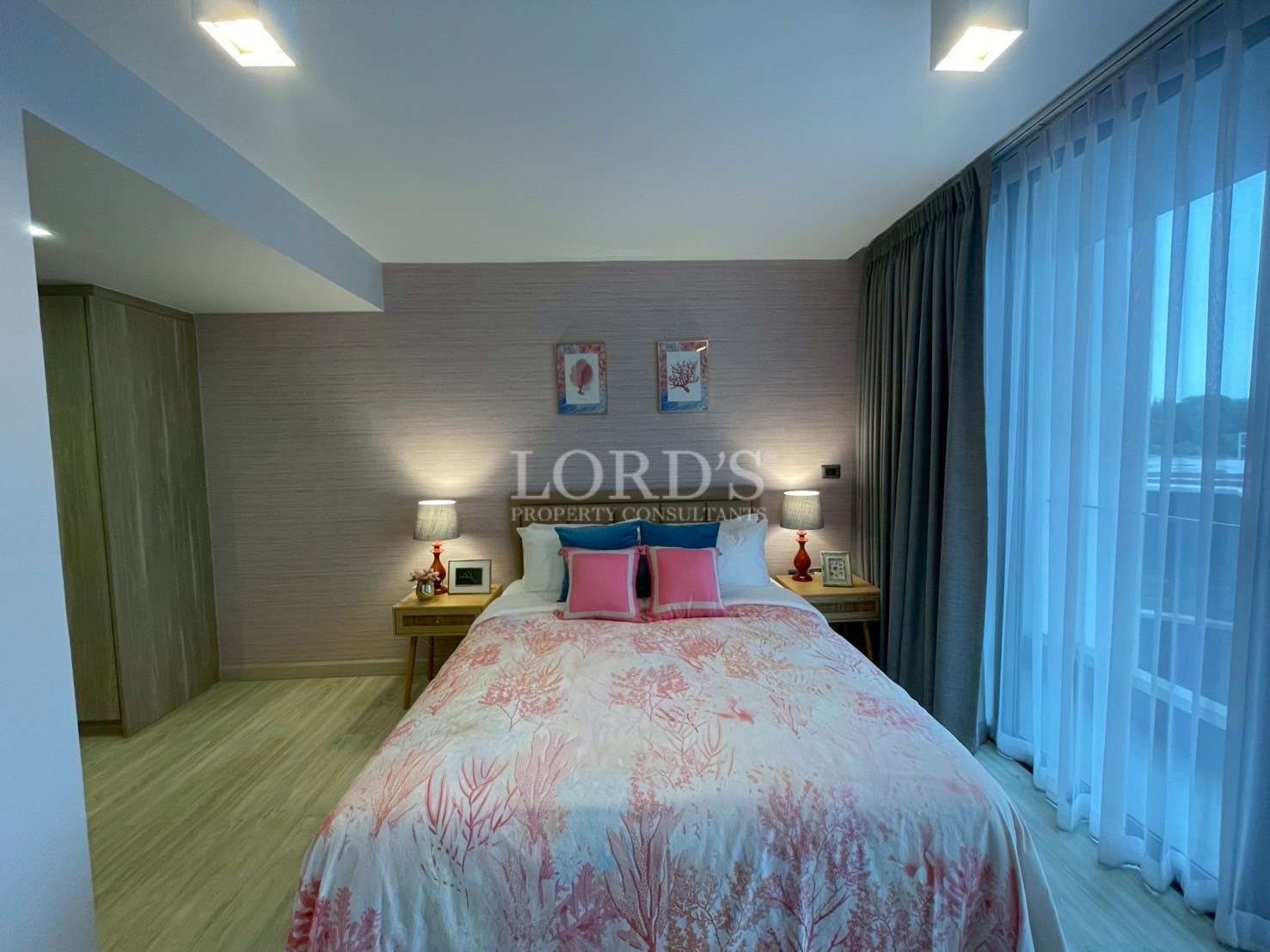 Cozy modern bedroom with double bed, bedside lamps, soft lighting, and floor-to-ceiling curtains.