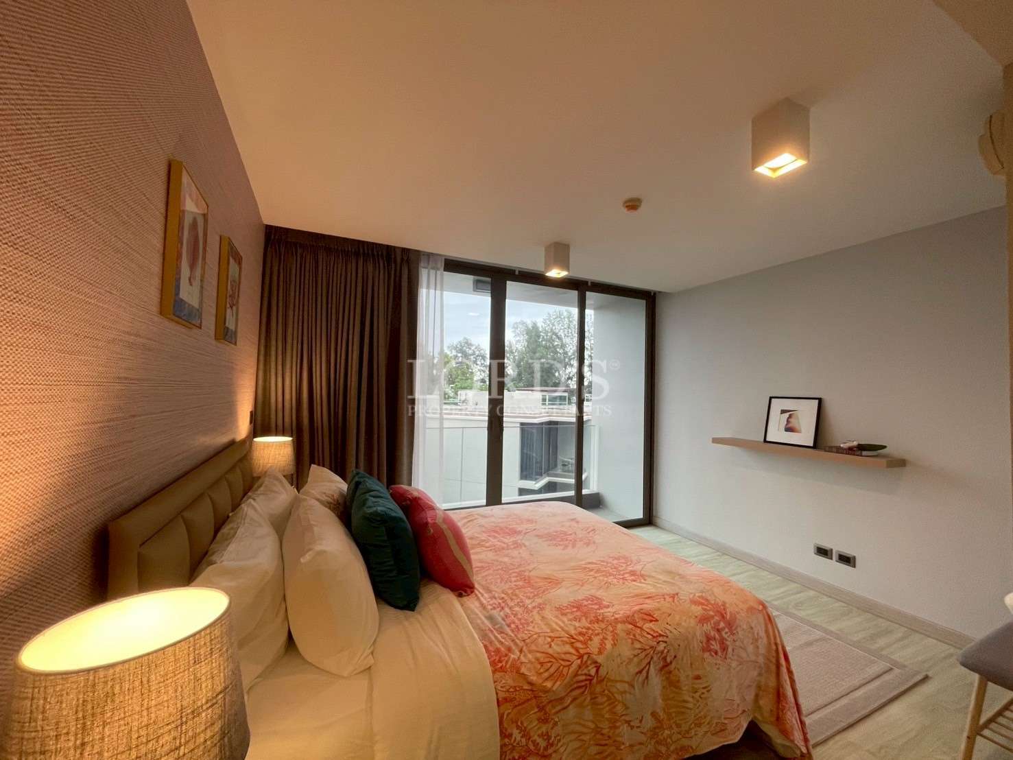 Modern bedroom with cozy lighting and sliding glass doors opening to a private balcony.