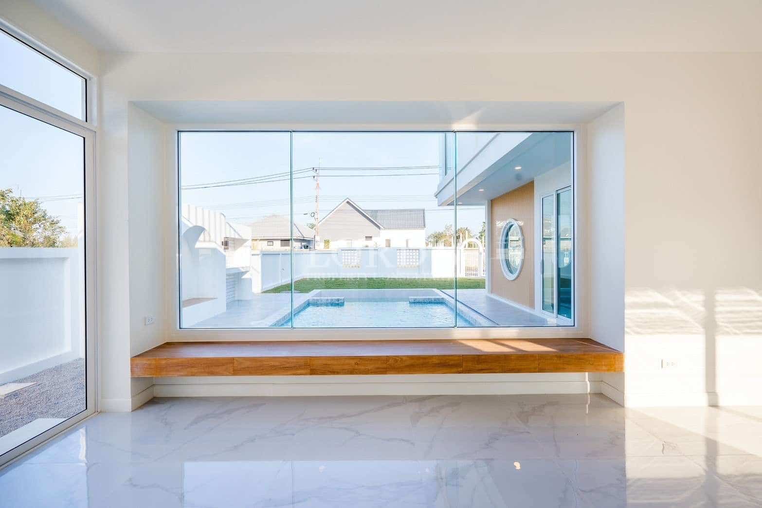 Modern living space with large glass window seat overlooking private swimming pool