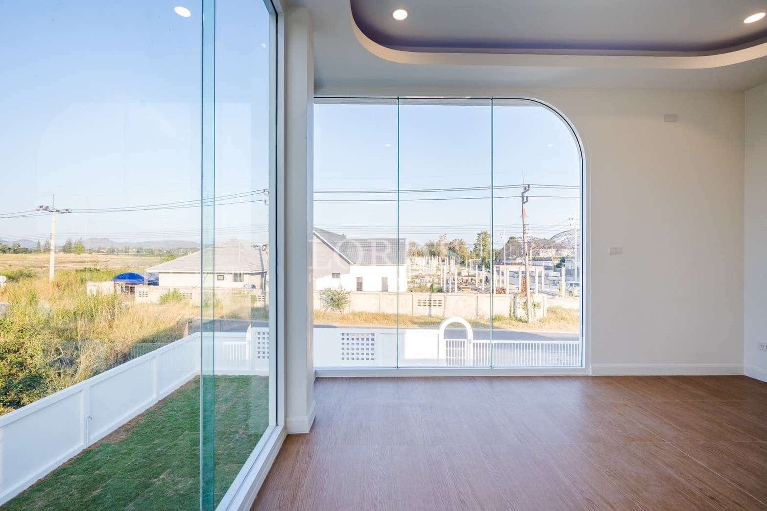 Bright empty room with curved floor-to-ceiling glass windows and wooden flooring