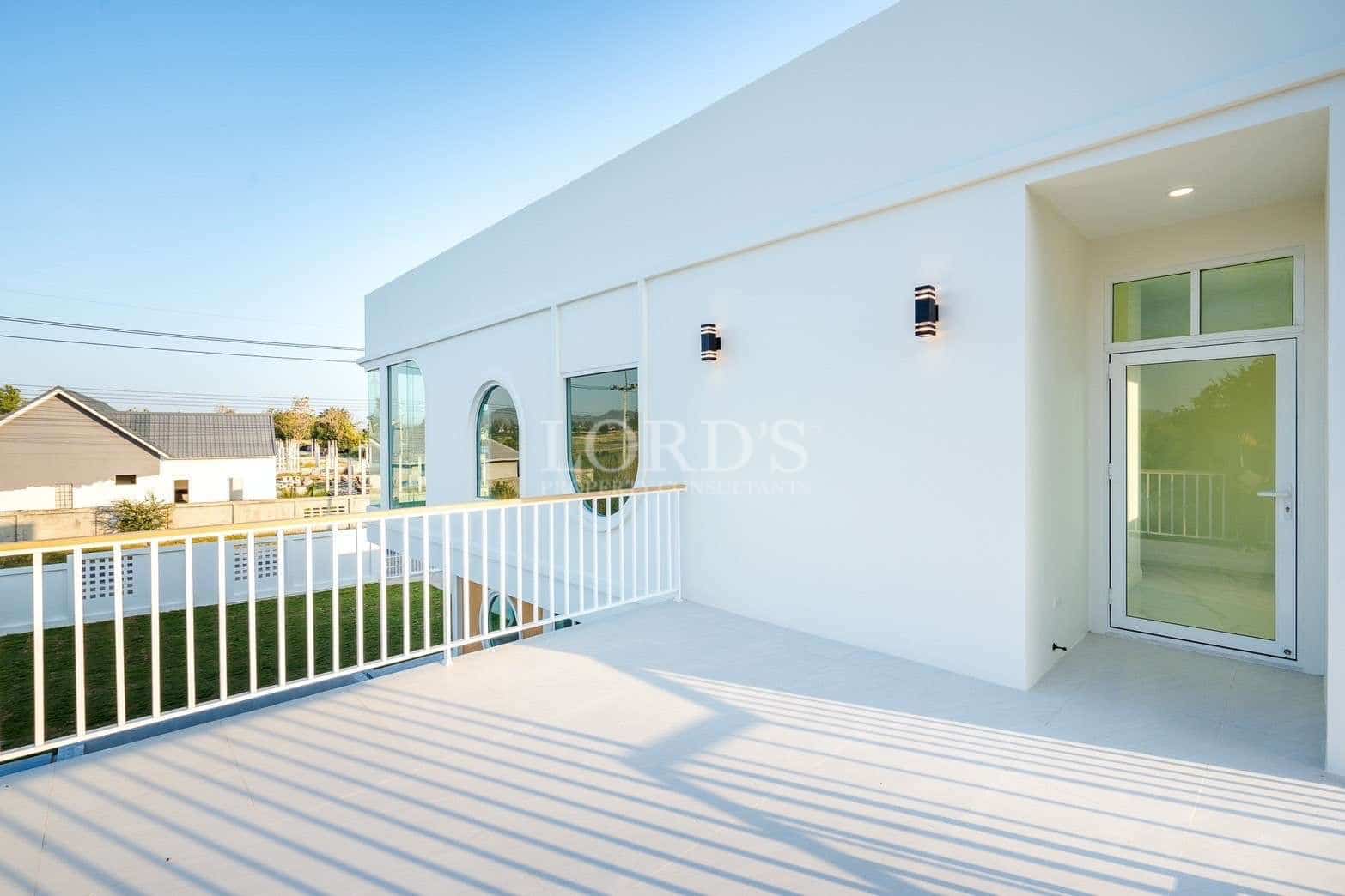 Modern balcony with white railing, glass door, and minimalist exterior design