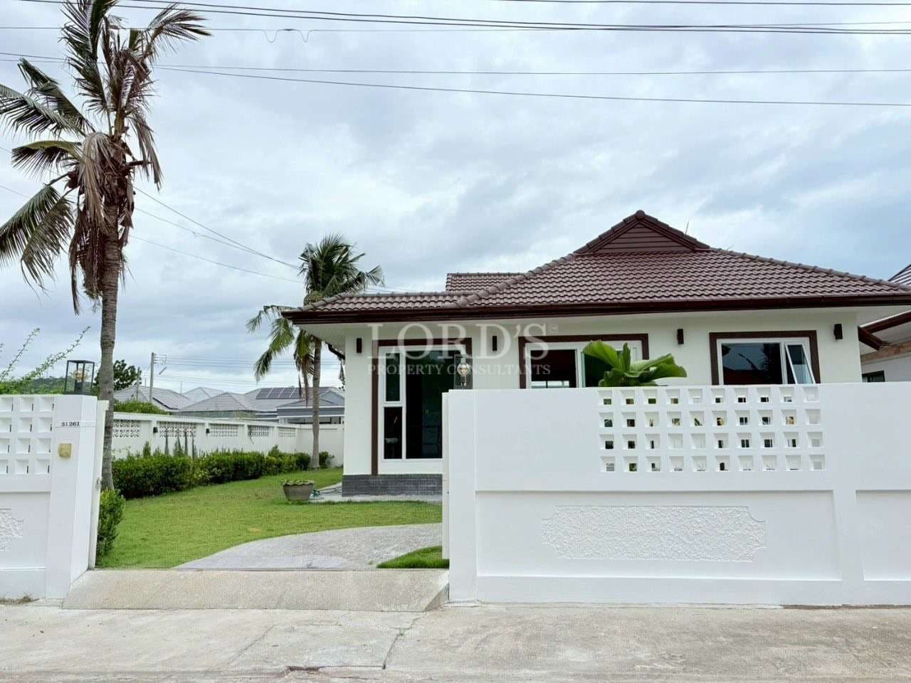 Modern single-story house with white boundary wall and green front yard