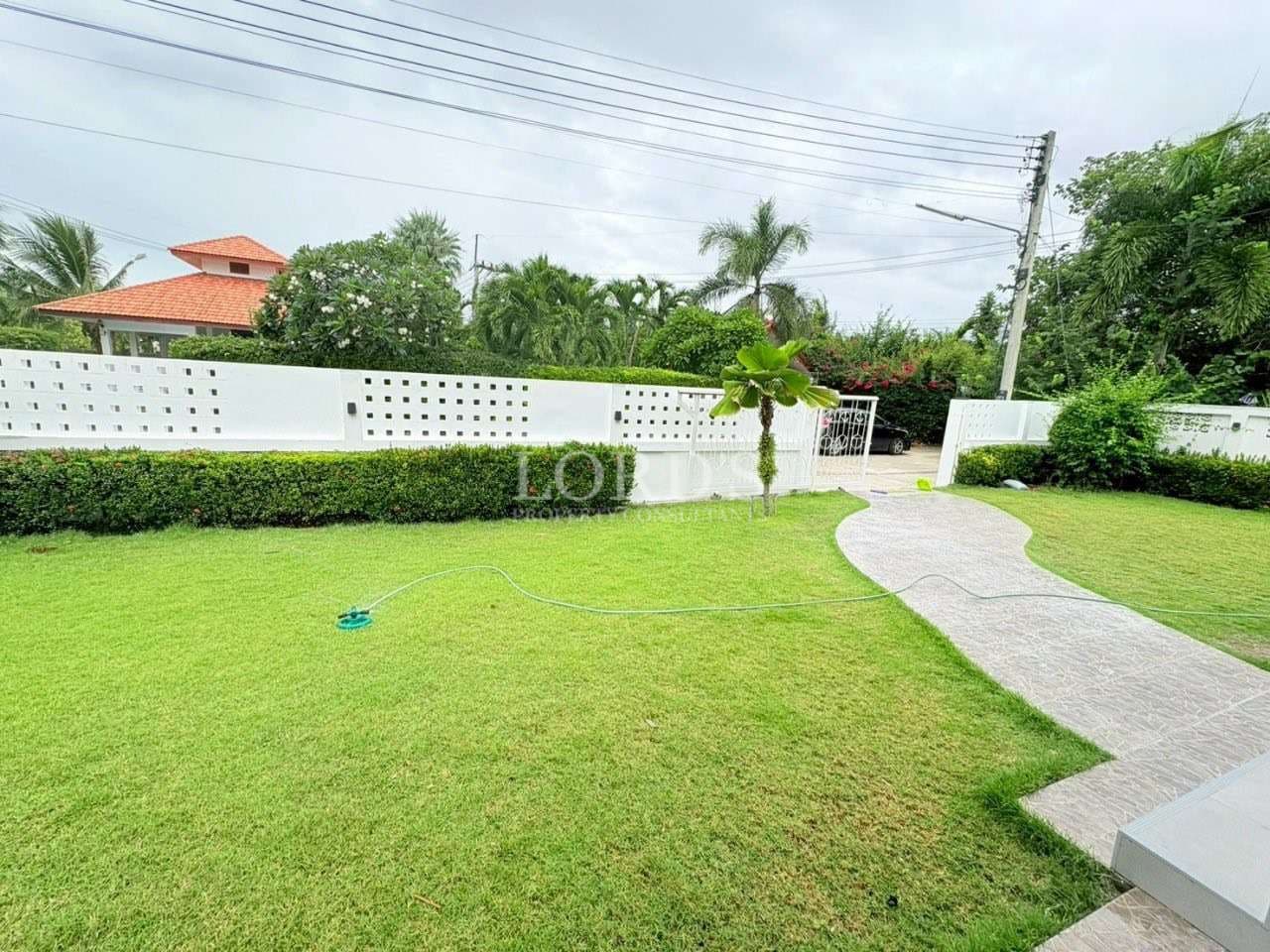 Green landscaped garden with curved walkway and white boundary wall