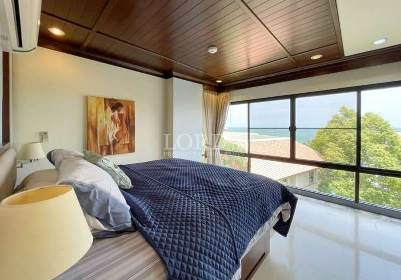 Ocean-view bedroom with large windows, wooden ceiling, and modern bed design