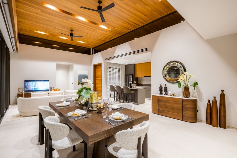 Luxury open-plan dining and living area with wooden ceiling, modern furniture, and kitchen island.