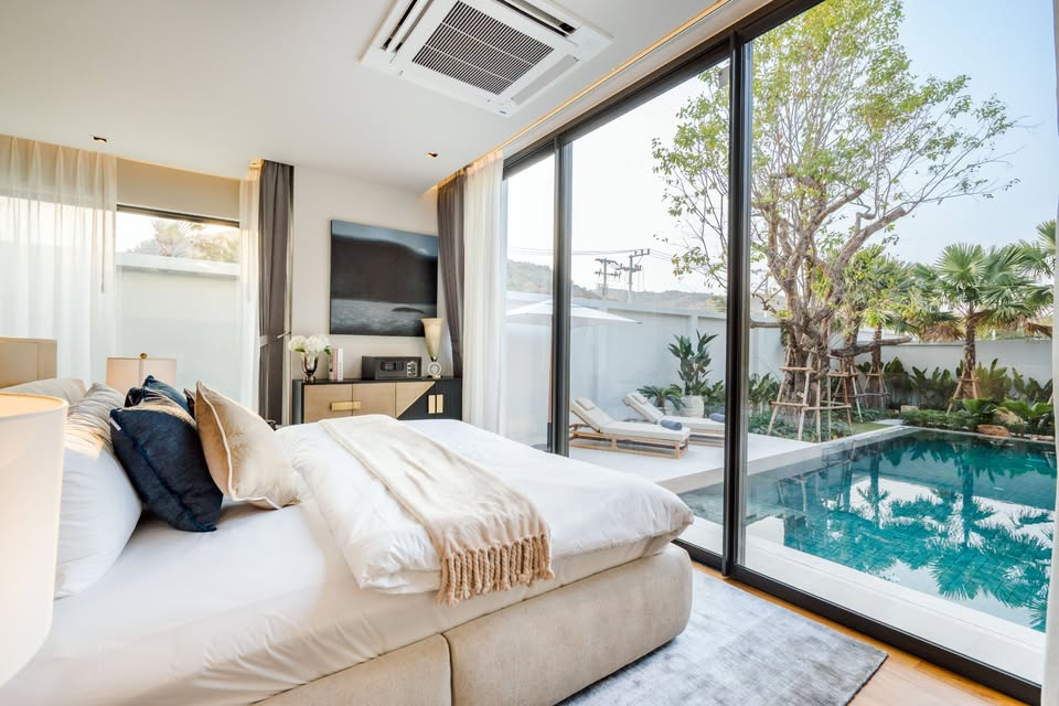 Luxury bedroom with pool view, king-size bed, and large glass sliding doors opening to a private swimming pool.