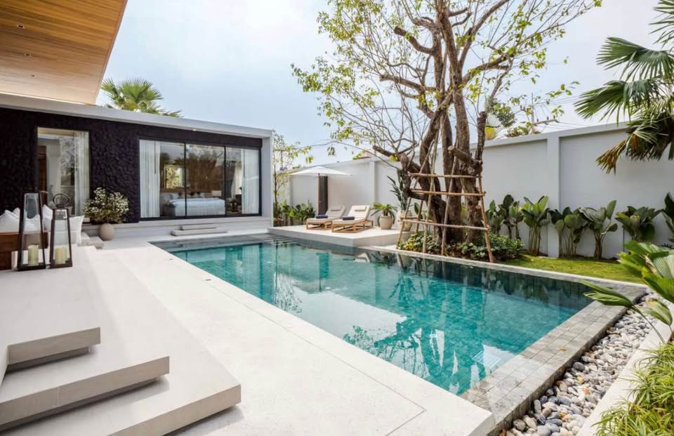 Modern luxury pool villa with private swimming pool, tropical garden, and bedroom with glass sliding doors.