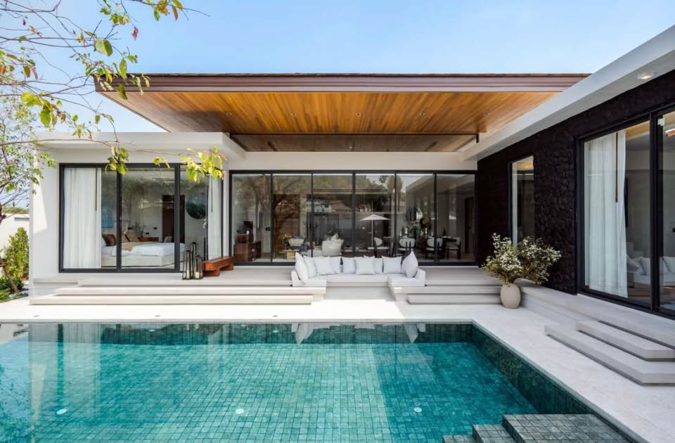 Modern luxury pool villa with private swimming pool, wooden roof ceiling, and large glass sliding doors.