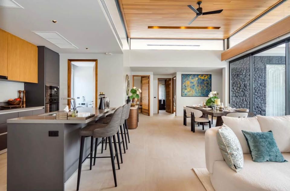 Modern open-plan living space with kitchen island, dining area, and large glass windows in a luxury home interior.