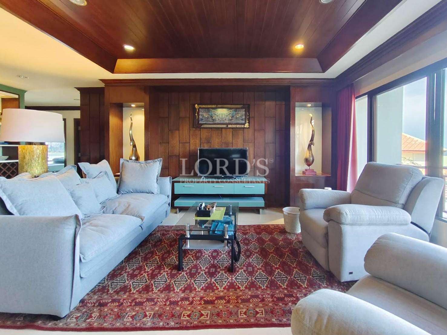 Elegant living room with wooden ceiling, modern sofas, TV unit, and decorative lighting