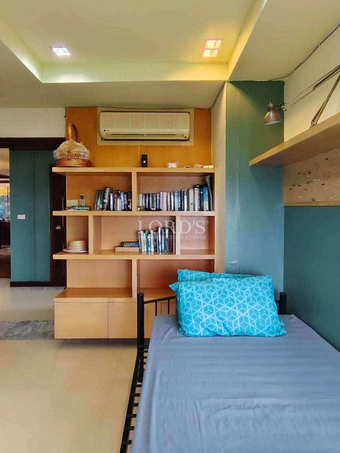 Modern bedroom with single bed, built-in bookshelf, wall-mounted air conditioner, and ambient lighting