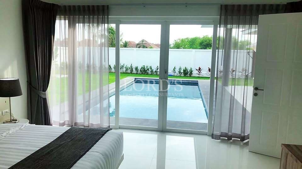 Bedroom with sliding glass doors opening to private pool and garden