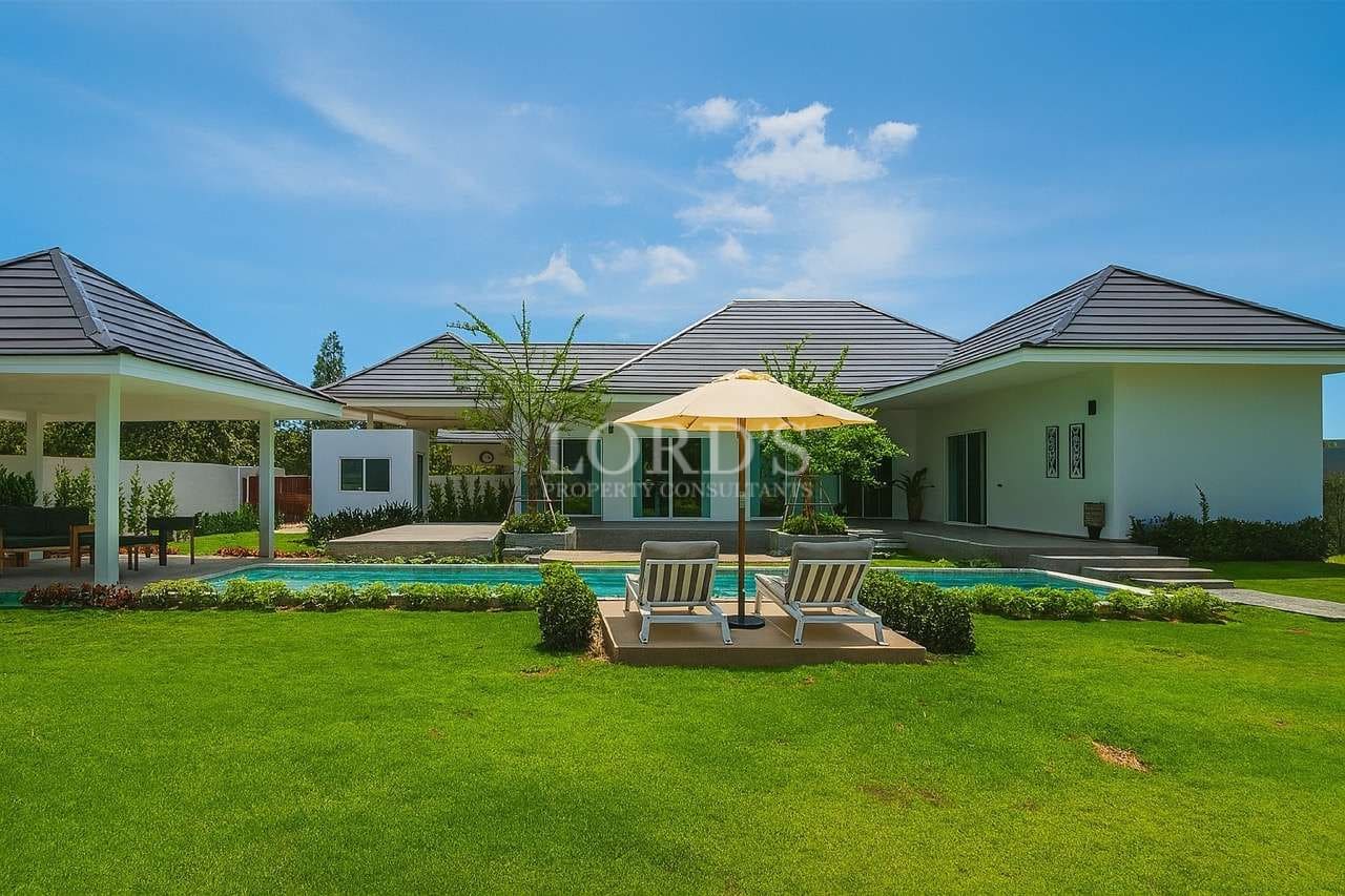 Modern luxury villa with private swimming pool, sun loungers, and landscaped garden