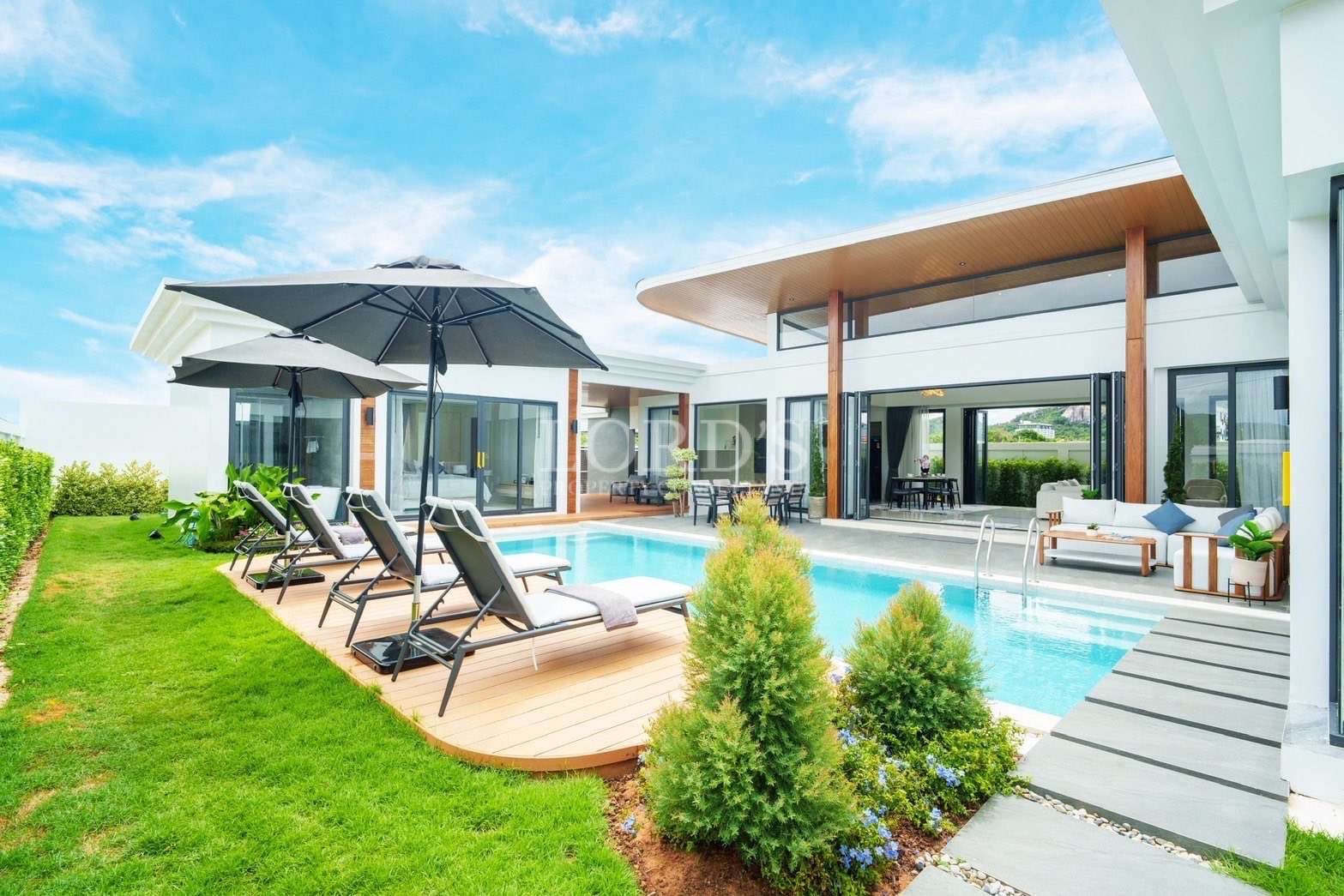 Modern luxury villa with private swimming pool, sun loungers, landscaped garden, and open-plan architecture.