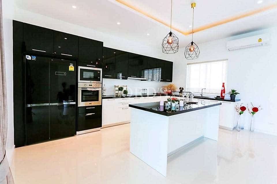 Luxury modern kitchen with black cabinets, white island, and pendant lighting